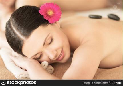 healthcare and beauty concept - picture of woman in spa salon with hot stones