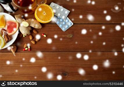healthcare and ethnoscience concept - traditional medicine and drug pills on wooden table over snow. traditional medicine and drugs