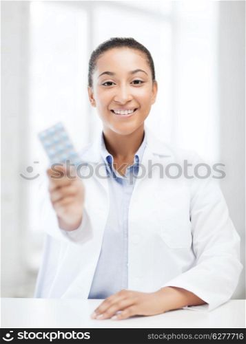 healthcare and medical concept - african doctor with blister packs of pills