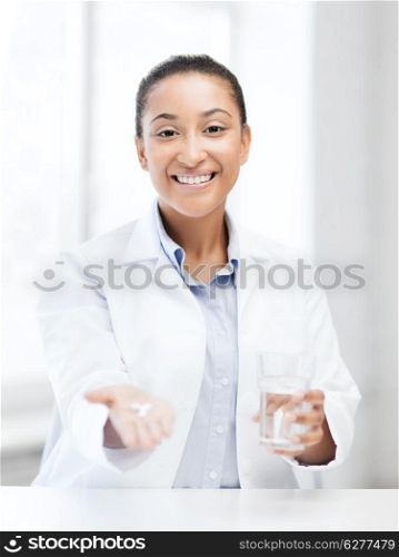 healthcare and medical concept - african doctor with offering pills and glass of water
