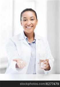 healthcare and medical concept - african doctor with offering pills and glass of water