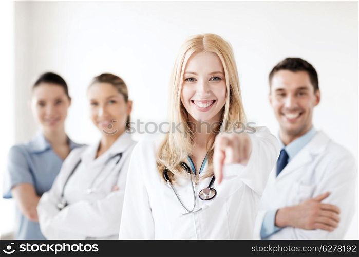 healthcare and medical concept - attractive female doctor in front of medical group