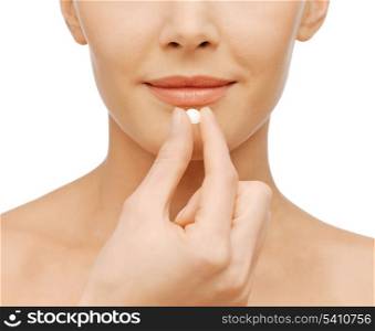 healthcare and medical concept - closeup picture of beautiful woman with pill