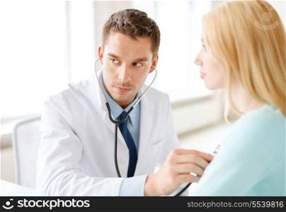 healthcare and medical concept - concentrated male doctor with stethoscope listening to the patient in hospital