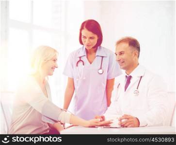 healthcare and medical concept - doctor and nurse with patient measuring blood pressure. doctor and patient in hospital
