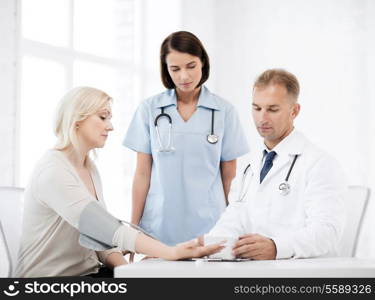 healthcare and medical concept - doctor and nurse with patient measuring blood pressure