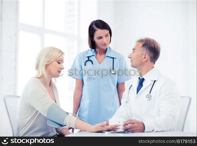 healthcare and medical concept - doctor and nurse with patient measuring blood pressure. doctor and patient in hospital