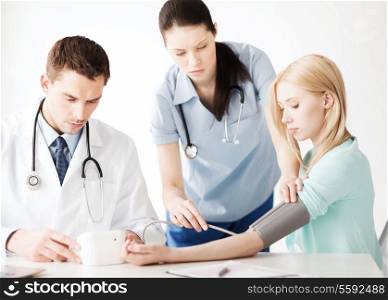 healthcare and medical concept - doctor and nurse with patient measuring blood pressure in hospital