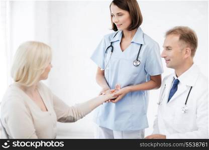 healthcare and medical concept - doctor and nurse with patient measuring pulse