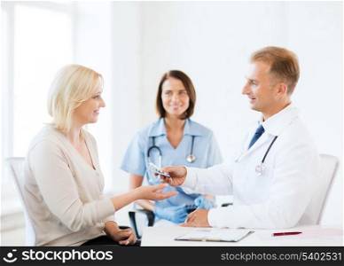 healthcare and medical concept - doctor giving tablets to patient in hospital