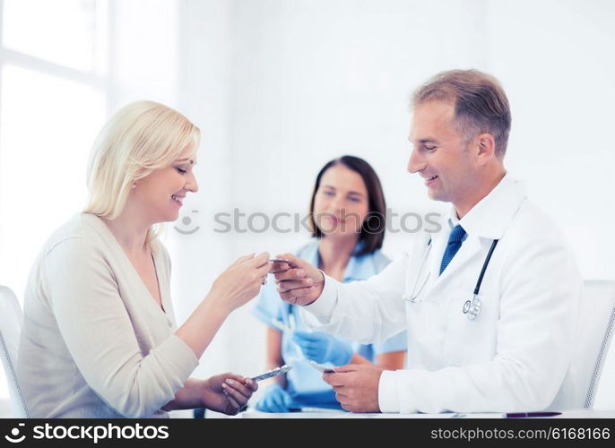 healthcare and medical concept - doctor giving tablets to patient in hospital. doctor giving tablets to patient in hospital