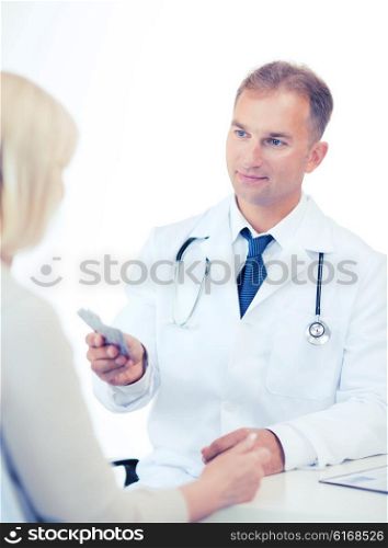 healthcare and medical concept - doctor giving tablets to patient in hospital. doctor giving tablets to patient in hospital