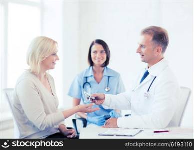 healthcare and medical concept - doctor giving tablets to patient in hospital. doctor giving tablets to patient in hospital
