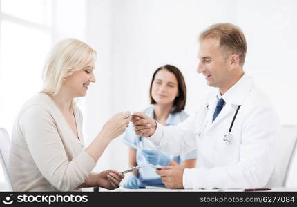 healthcare and medical concept - doctor giving tablets to patient in hospital