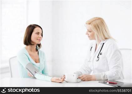 healthcare and medical concept - doctor measuring patient&#39;s blood pressure