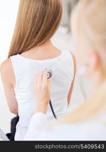 healthcare and medical concept - doctor with stethoscope listening to child back in hospital