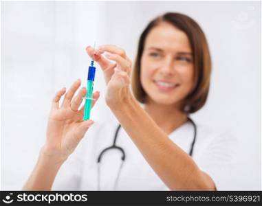 healthcare and medical concept - female doctor holding syringe with injection