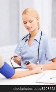 healthcare and medical concept - female doctor or nurse with patient measuring blood pressure