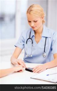 healthcare and medical concept - female doctor or nurse with patient measuring blood sugar value