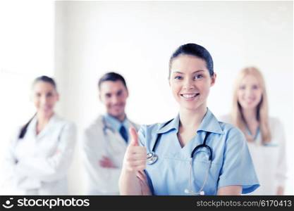 healthcare and medical concept - female doctor with group of medics showing thumbs up. doctor with group of medics showing thumbs up