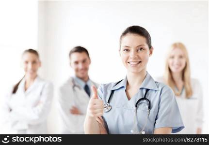 healthcare and medical concept - female doctor with group of medics showing thumbs up