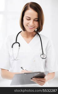 healthcare and medical concept - female doctor with stethoscope writing prescription