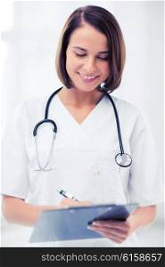 healthcare and medical concept - female doctor with stethoscope writing prescription. female doctor with stethoscope and clipboard