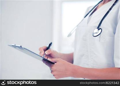 healthcare and medical concept - female doctor with stethoscope writing prescription. female doctor with stethoscope and prescription