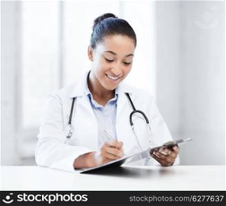 healthcare and medical concept - female doctor with stethoscope writing prescription