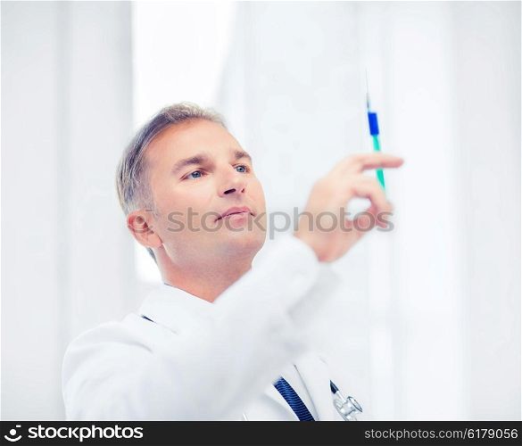 healthcare and medical concept - male doctor holding syringe with injection. male doctor holding syringe with injection