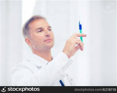 healthcare and medical concept - male doctor holding syringe with injection. male doctor holding syringe with injection