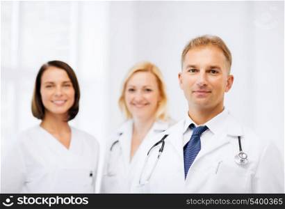 healthcare and medical concept - male doctor with stethoscope and colleagues