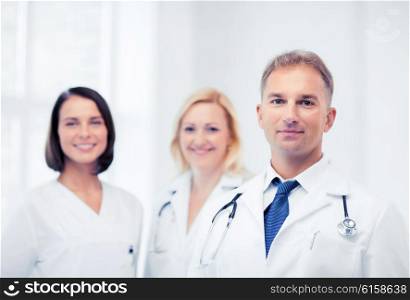 healthcare and medical concept - male doctor with stethoscope and colleagues. doctor with stethoscope and colleagues