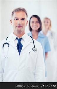 healthcare and medical concept - male doctor with stethoscope and colleagues. doctor with stethoscope and colleagues
