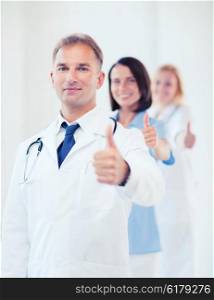 healthcare and medical concept - male doctor with stethoscope and colleagues showing thumbs up. doctor with stethoscope and colleagues