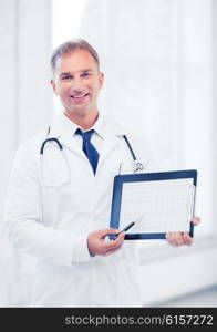 healthcare and medical concept - male doctor with stethoscope showing cardiogram. male doctor with stethoscope showing cardiogram