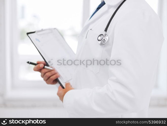 healthcare and medical concept - male doctor with stethoscope writing prescription