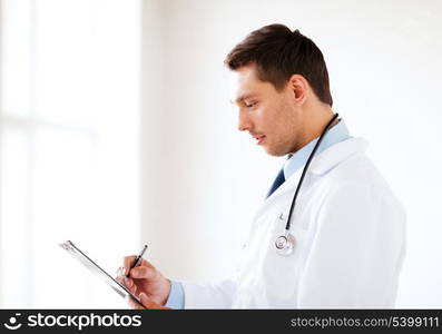 healthcare and medical concept - male doctor with stethoscope writing prescription