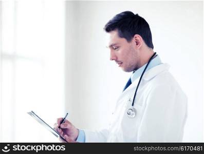 healthcare and medical concept - male doctor with stethoscope writing prescription. male doctor with stethoscope writing prescription