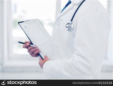 healthcare and medical concept - male doctor with stethoscope writing prescription. male doctor with stethoscope writing prescription