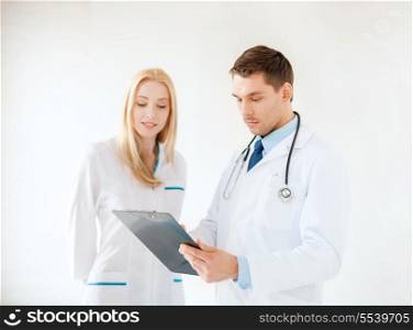 healthcare and medical concept - smiling young male doctor with stethoscope and clipboard and female nurse in hospital