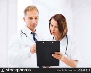 healthcare and medical concept - two doctors discussing diagnosis