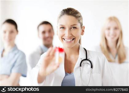 healthcare and medical concept - young female doctor with jar of capsules