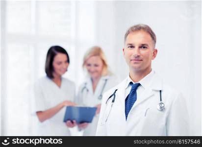 healthcare and medical concept - young male doctor with colleagues in hospital. male doctor with colleagues
