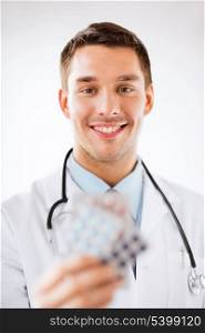 healthcare and medical concept - young male doctor with packs of pills