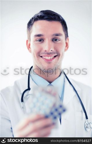 healthcare and medical concept - young male doctor with packs of pills. young male doctor with packs of pills