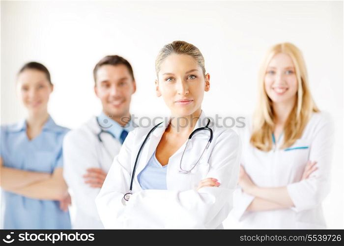 healthcare and medicine concept - attractive female doctor in front of medical group in hospital