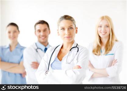 healthcare and medicine concept - attractive female doctor in front of medical group in hospital