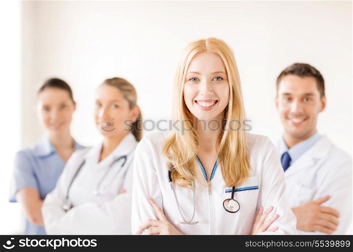 healthcare and medicine concept - attractive female doctor or nurse in front of medical group in hospital