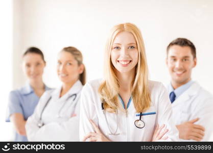 healthcare and medicine concept - attractive female doctor or nurse in front of medical group in hospital